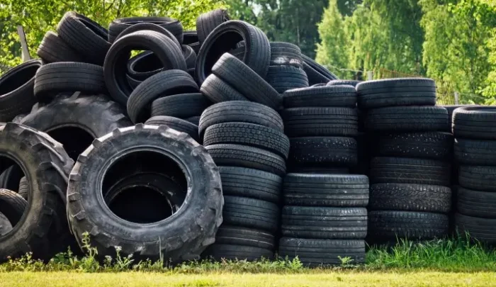 Stack of used tires on top of grass.