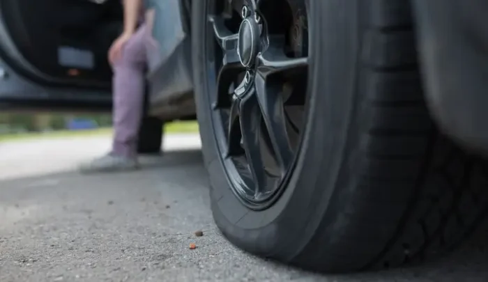 Woman with broken down car because of a flat tire.